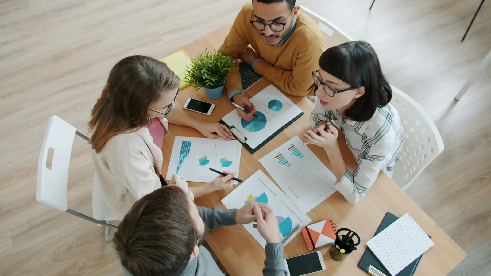 Vier Personen sitzen an einem Tisch mit ausgedruckten Diagrammen und besprechen die Auswertung.