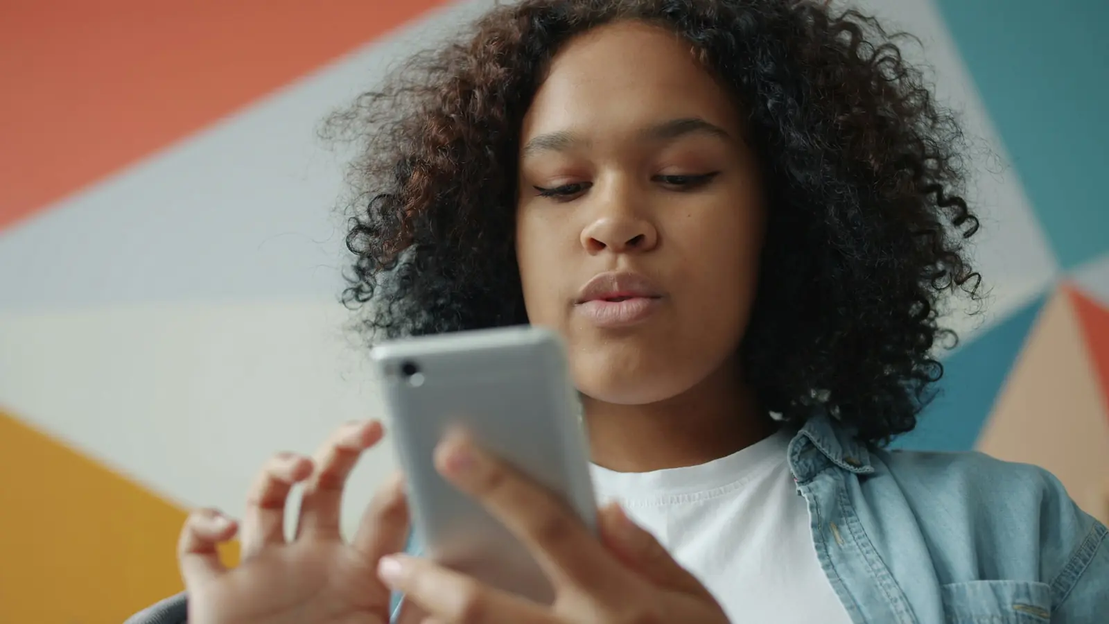 Eine junge Frau tippt konzentriert auf ihrem Smartphone.